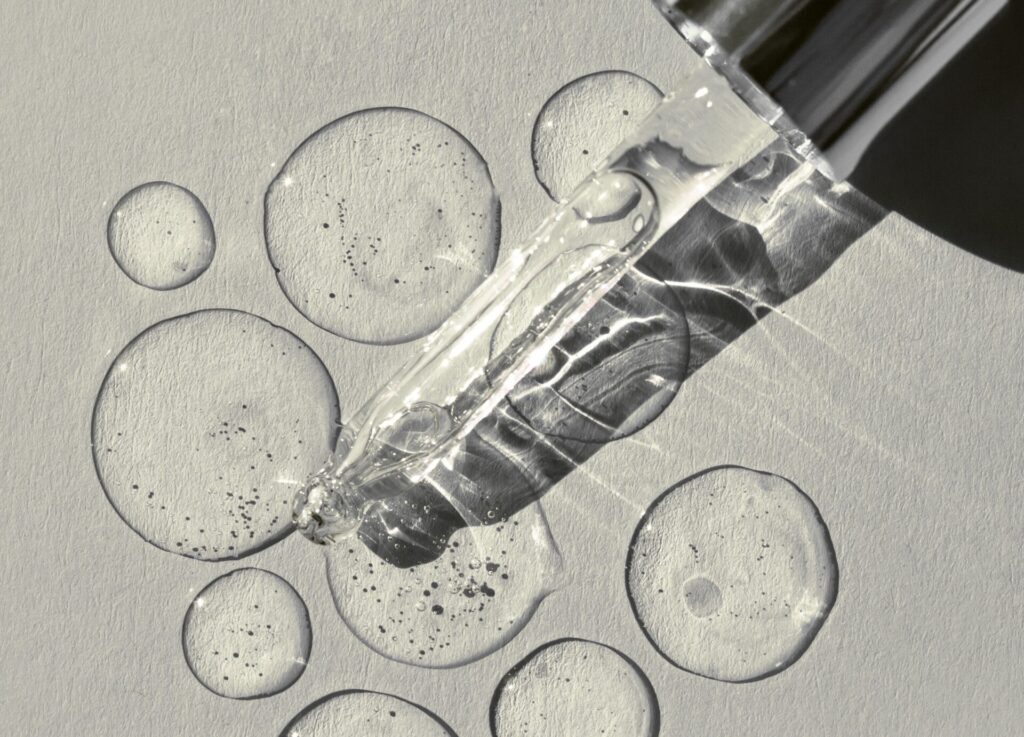 Glass dropper dispensing clear serum droplets